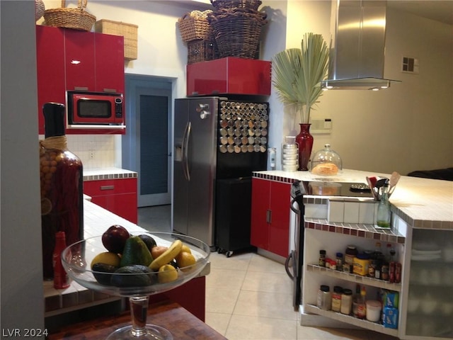 kitchen with range, island range hood, stainless steel fridge, and light tile patterned flooring