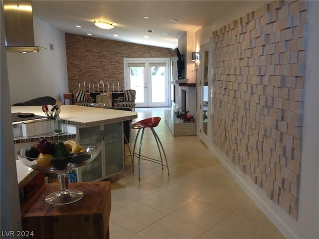 kitchen featuring french doors, a breakfast bar, vaulted ceiling, and light tile patterned floors