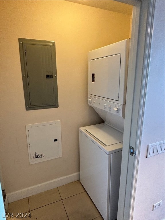 washroom featuring stacked washer and dryer, light tile patterned floors, and electric panel