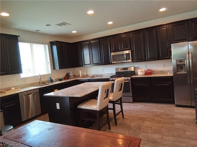 kitchen featuring a center island, appliances with stainless steel finishes, sink, and a kitchen bar