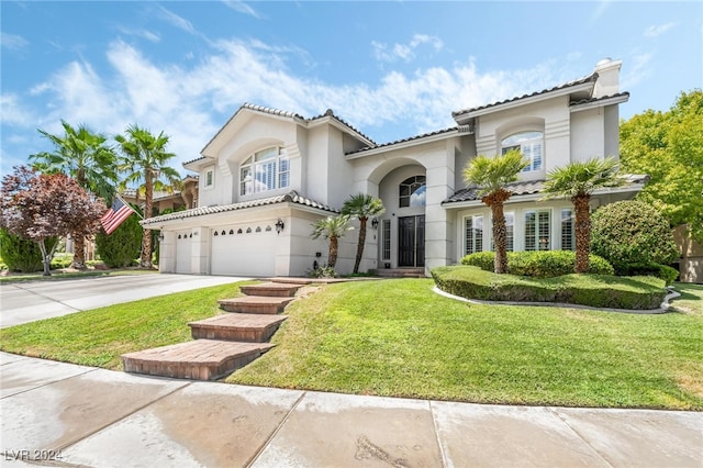 mediterranean / spanish house with a garage and a front lawn