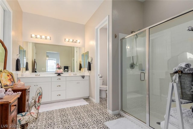 full bath with a sink, double vanity, a shower stall, and toilet