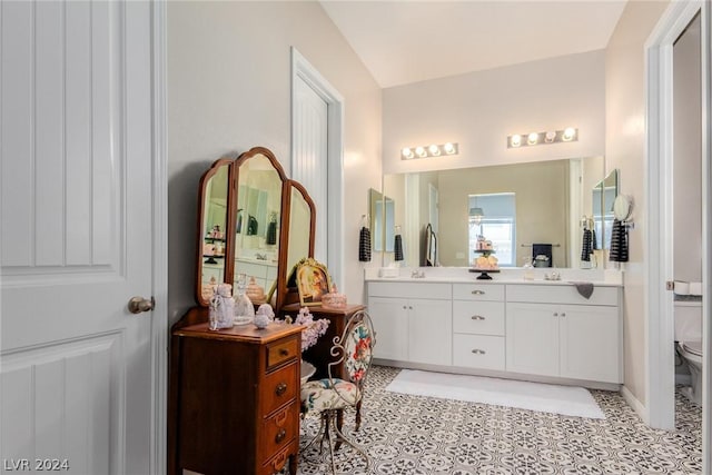 bathroom featuring double vanity, toilet, lofted ceiling, tile patterned floors, and a sink