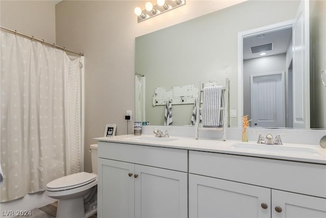 bathroom featuring toilet, double vanity, a sink, and visible vents