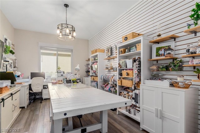 home office with dark wood-type flooring and an inviting chandelier