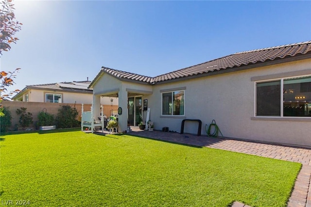 rear view of house featuring stucco siding, a lawn, a patio area, fence, and a tiled roof