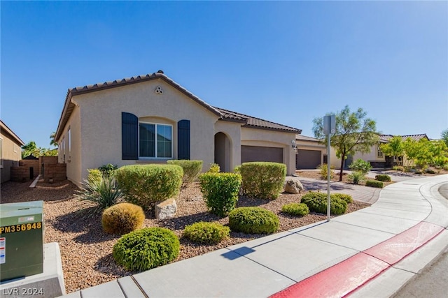 mediterranean / spanish-style house with a tile roof, an attached garage, and stucco siding