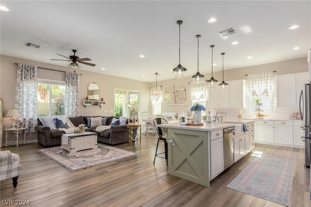 kitchen featuring a breakfast bar, light countertops, a center island with sink, and white cabinetry