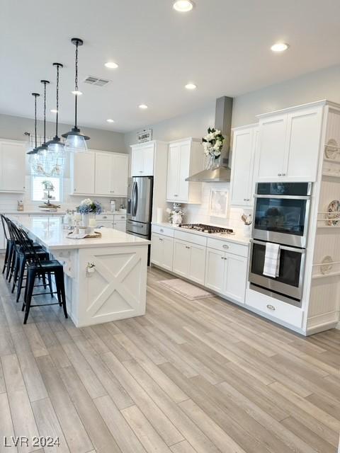 kitchen featuring stainless steel appliances, a kitchen bar, light countertops, and decorative light fixtures