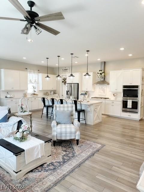 living area with ceiling fan, light wood-style flooring, and recessed lighting