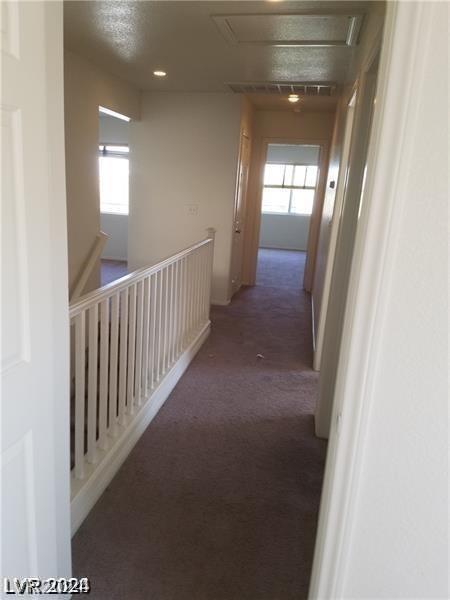 corridor with dark colored carpet and a wealth of natural light