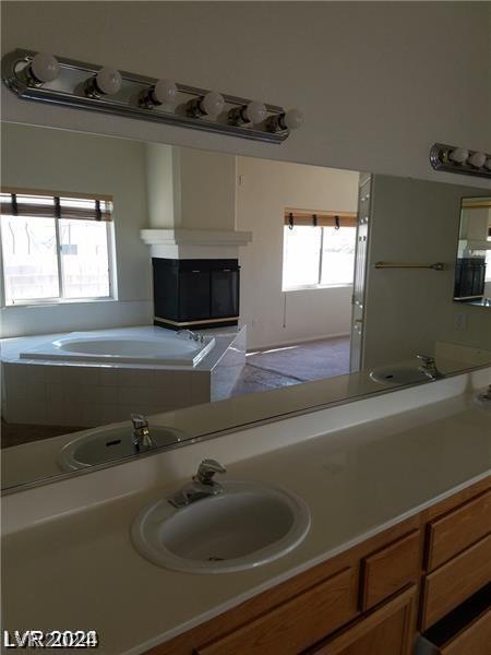 bathroom featuring tiled bath, a wealth of natural light, and vanity