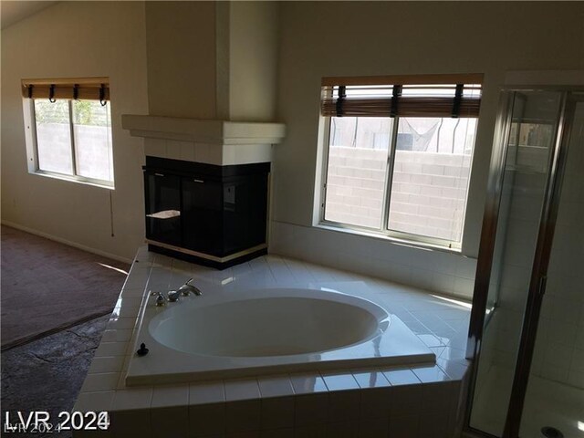 bathroom with lofted ceiling, a tiled fireplace, and plus walk in shower