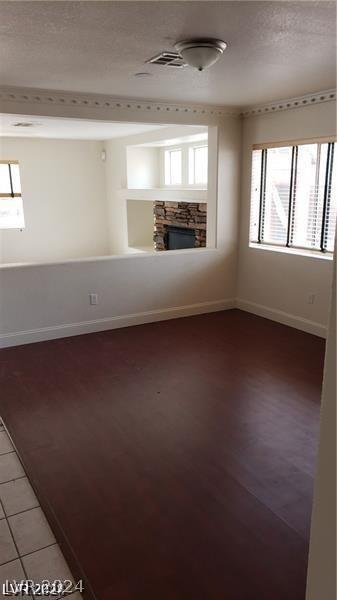 unfurnished room with a stone fireplace, a textured ceiling, and hardwood / wood-style flooring