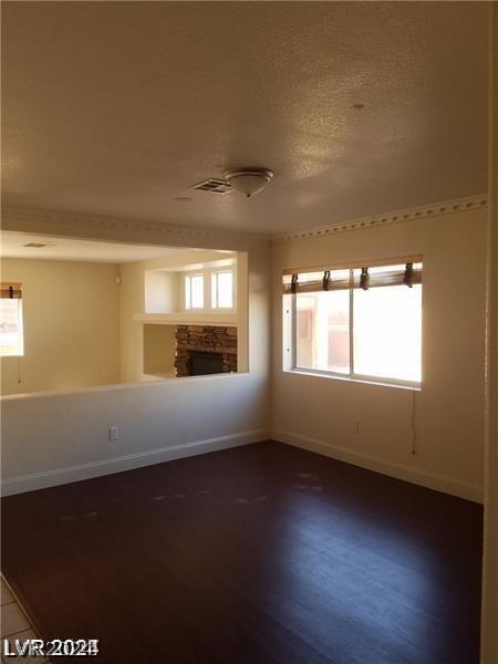 unfurnished room with a fireplace, a textured ceiling, and wood-type flooring