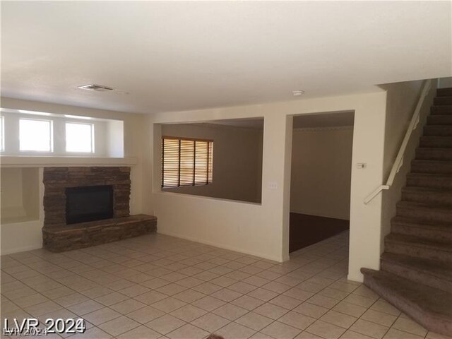 unfurnished living room featuring a fireplace and light tile patterned floors