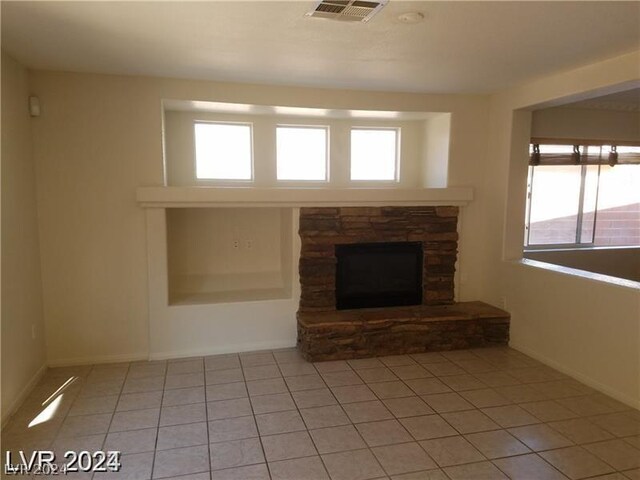 unfurnished living room with a fireplace, a healthy amount of sunlight, and light tile patterned floors