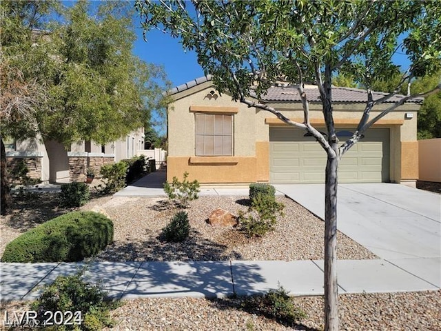 view of front of house featuring fence, a tile roof, stucco siding, a garage, and driveway