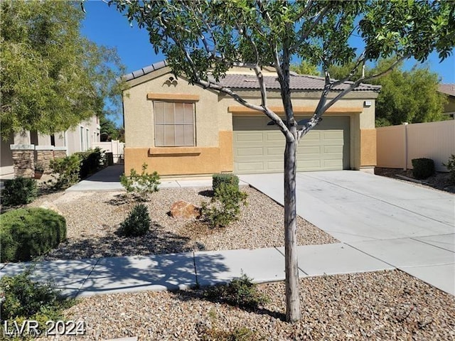 view of front of property with stucco siding, an attached garage, a tile roof, and fence