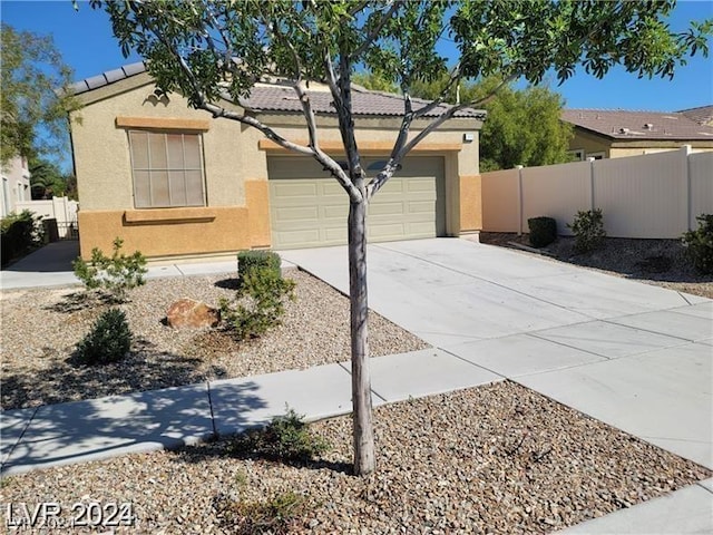 view of front of property featuring stucco siding, fence, an attached garage, and a tile roof