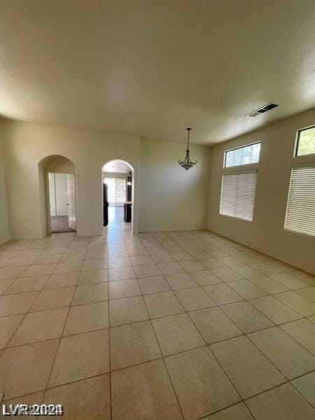 spare room with light tile patterned floors, visible vents, and arched walkways