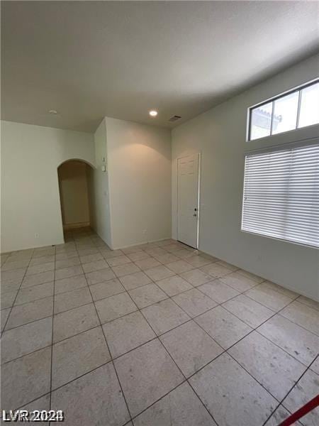 unfurnished room featuring arched walkways, visible vents, and light tile patterned flooring