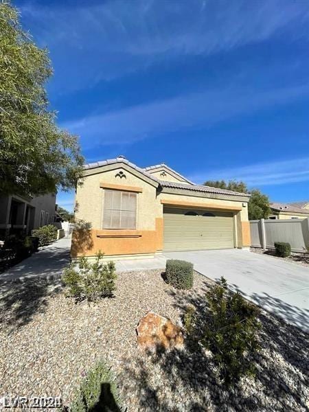 ranch-style house with fence, an attached garage, stucco siding, concrete driveway, and a tile roof