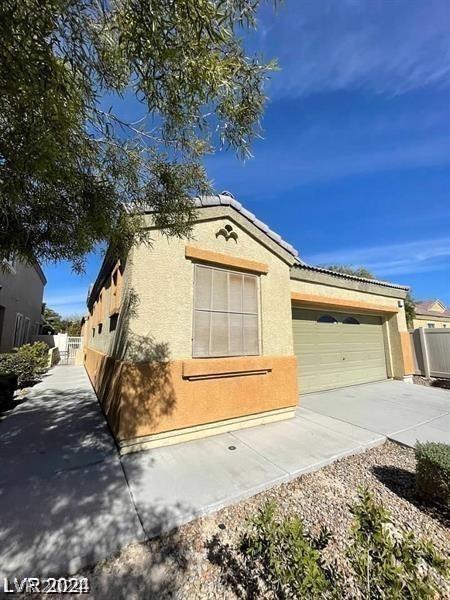 ranch-style home featuring stucco siding, a garage, driveway, and fence