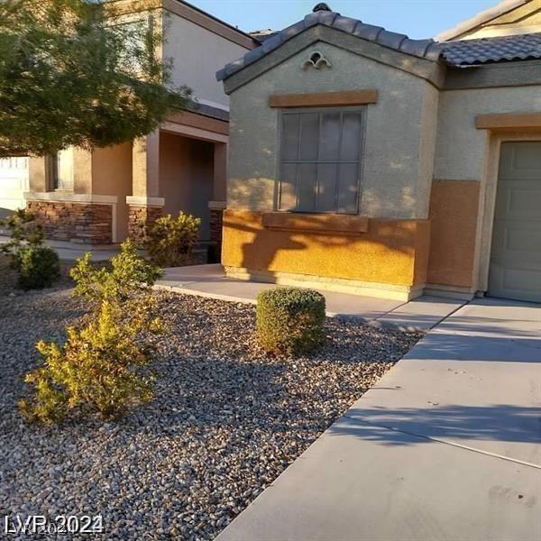 doorway to property featuring a tiled roof, an attached garage, and stucco siding