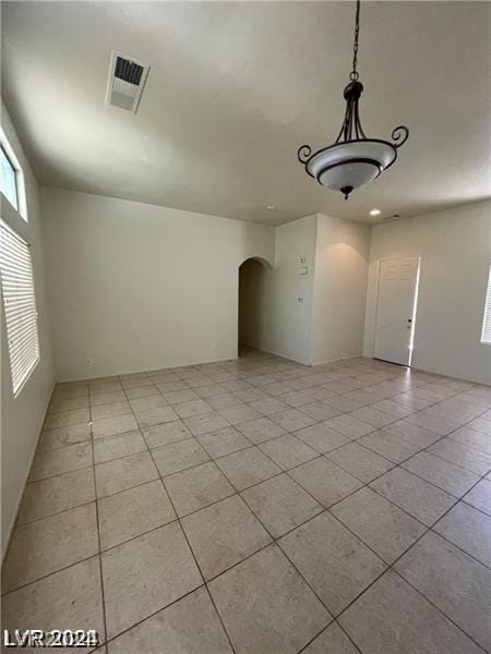 spare room with arched walkways, visible vents, and light tile patterned floors