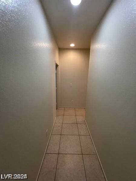 corridor with light tile patterned floors and baseboards