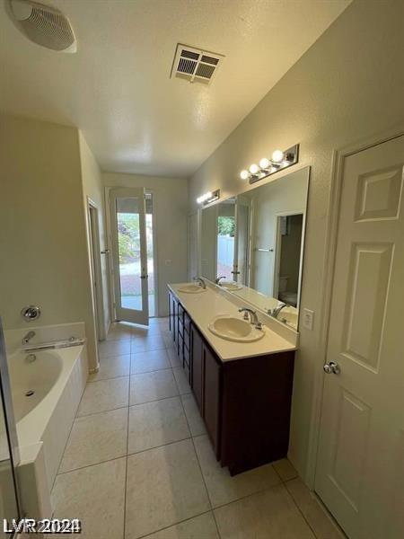 full bathroom featuring tile patterned floors, a bath, visible vents, and a sink