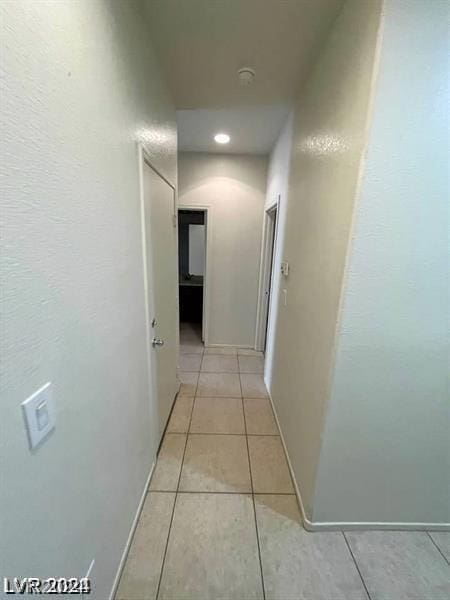 hallway featuring light tile patterned floors and baseboards