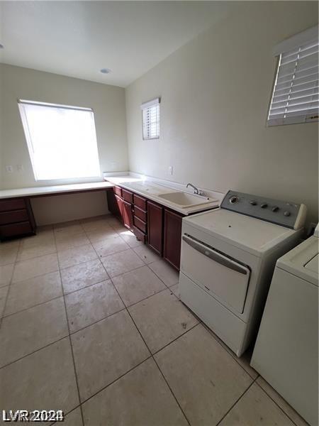 laundry area featuring cabinet space, independent washer and dryer, light tile patterned flooring, and a sink