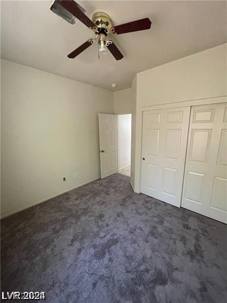 unfurnished bedroom with a ceiling fan, dark colored carpet, and a closet