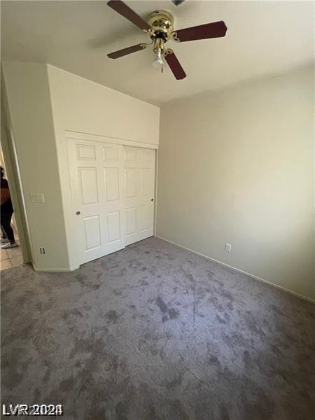 unfurnished bedroom featuring a closet, carpet, and a ceiling fan