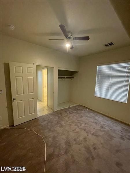 unfurnished bedroom with a ceiling fan, carpet, visible vents, and a closet