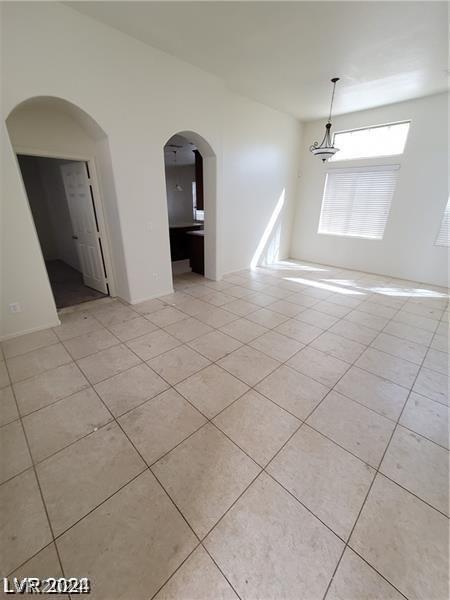 unfurnished room featuring light tile patterned floors and arched walkways