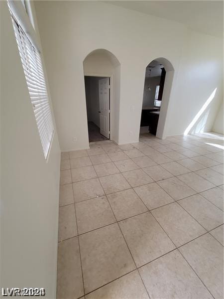 spare room with arched walkways and light tile patterned flooring