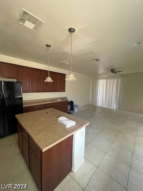 kitchen featuring visible vents, a center island, open floor plan, pendant lighting, and freestanding refrigerator