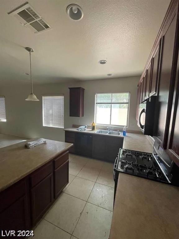 kitchen with visible vents, dark brown cabinetry, light tile patterned flooring, a textured ceiling, and a sink