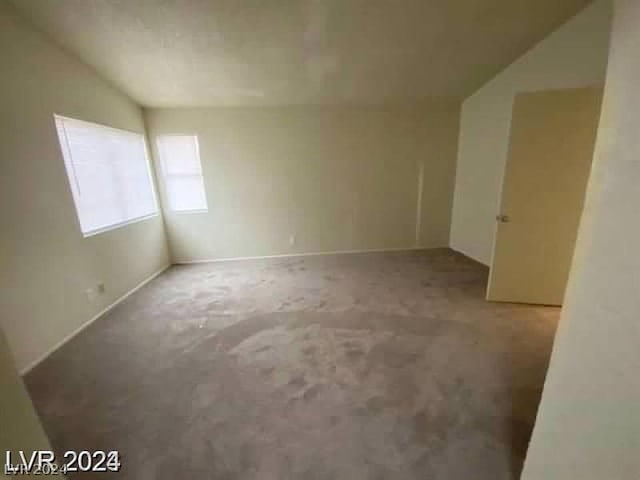 carpeted spare room with vaulted ceiling