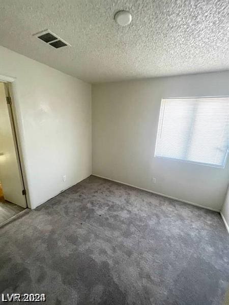 carpeted empty room with a textured ceiling