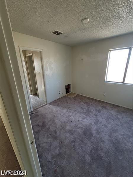 carpeted empty room with a textured ceiling