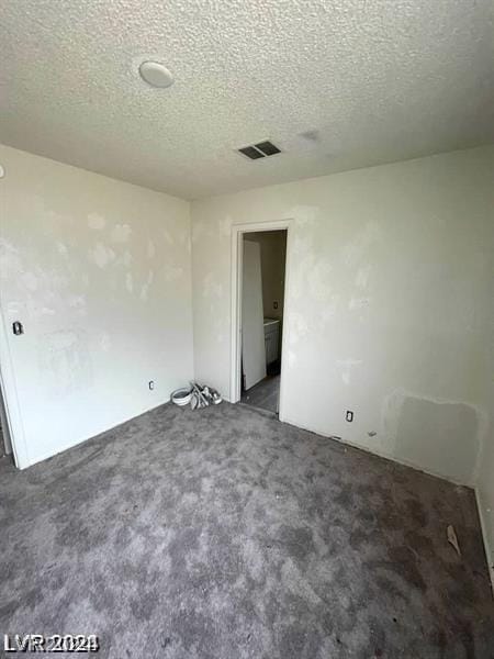 empty room featuring dark carpet and a textured ceiling