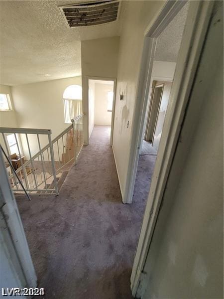 hallway with carpet and a textured ceiling