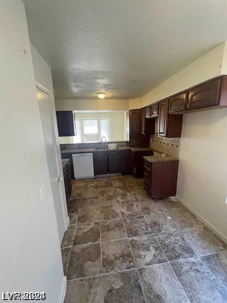 kitchen featuring dark brown cabinets, sink, white dishwasher, and decorative backsplash