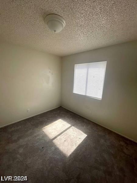 carpeted empty room featuring a textured ceiling