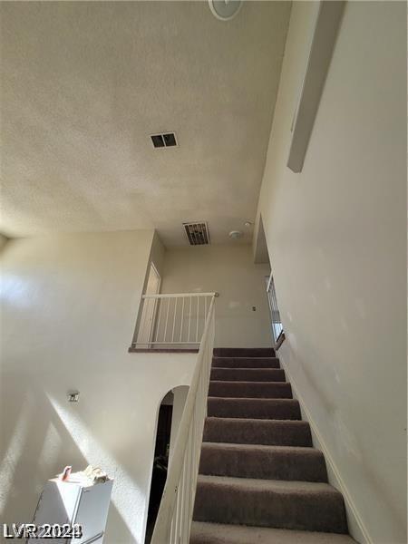 staircase featuring a textured ceiling