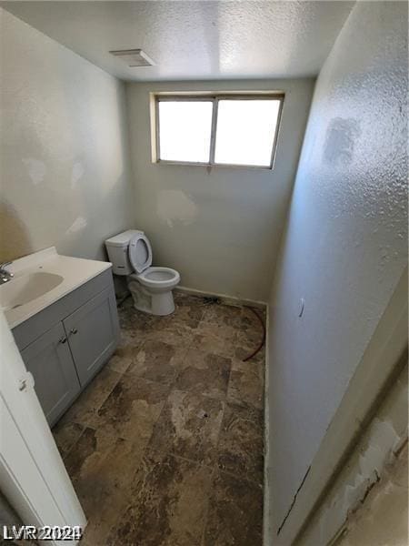 bathroom with vanity, a textured ceiling, and toilet